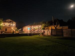 a backyard at night with a house and a fence at Pensiunea Lotus Corbu in Corbu