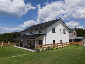 a white house with a fence and a yard at APARTMÁNY POD SJEZDOVKOU in Abertamy