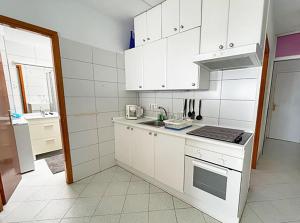 a kitchen with white cabinets and a stove top oven at Ocean Kiss Apartment in Puerto del Carmen