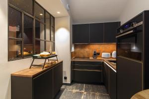 kuchnia z czarnymi szafkami i blatem w obiekcie Loft Room 85, petite maison avec jacuzzi privatif w mieście Les Sables-dʼOlonne
