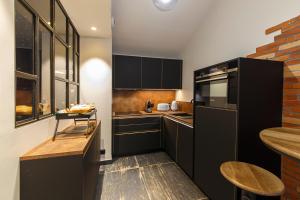 uma cozinha com armários pretos e uma parede de tijolos em Loft Room 85, petite maison avec jacuzzi privatif em Les Sables-dʼOlonne