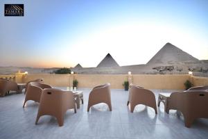 un patio con tavoli e sedie con piramidi sullo sfondo di Tamara Pyramids View a Il Cairo
