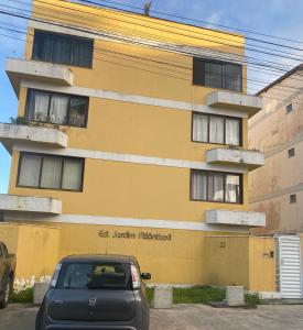 a car parked in front of a yellow building at Temporada Ilheus na Praia dos Milionarios Kitnet in Ilhéus
