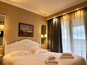 Un dormitorio con una cama blanca con toallas. en Anemolia Resort and Spa, en Ioannina