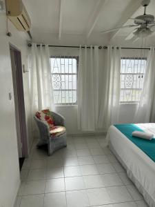 a bedroom with a bed and a chair and windows at Home2Home Guesthouse in Christ Church