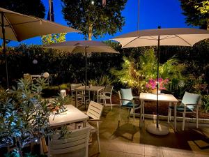 due tavoli e sedie con ombrelloni su un patio di Hotel Alfieri a Sirmione