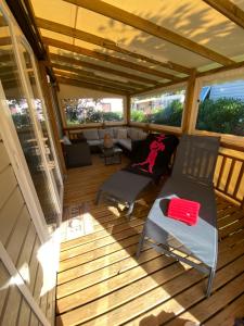 eine abgeschirmte Veranda mit einem Stuhl und einem Sofa in der Unterkunft Mobil home de charme in Fréjus