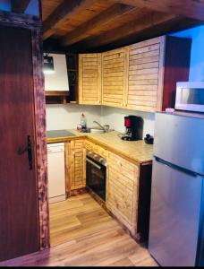 a kitchen with wooden cabinets and a white refrigerator at Chalet 8 couchages à 100m du bas des pistes et commerces in Les Angles