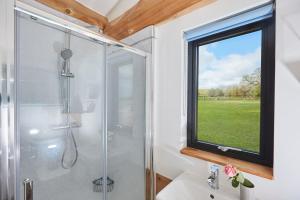 baño con ducha y ventana en Waters Edge Retreat, en Naseby
