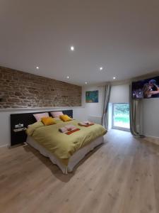 ein Schlafzimmer mit einem großen Bett und einer Ziegelwand in der Unterkunft Les étangs du moulin d'Harcy in Lonny