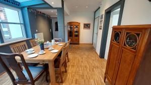 a dining room with a wooden table with chairs and a kitchen at Ferienwohnung Am Freitagsbach in Celle