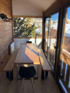 einen Tisch und Stühle in einem Zimmer mit Fenstern in der Unterkunft Chalet 8 couchages à 100m du bas des pistes et commerces in Les Angles