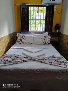 Una cama con sábanas blancas y flores rojas. en Casa Goio Morro de São Paulo, en Morro de São Paulo