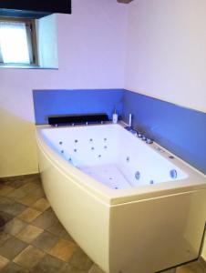 uma banheira branca num quarto com uma parede azul em Chambres d'hôtes La Moraine Enchantée em Aosta