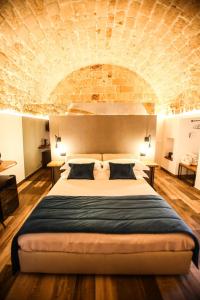 a bedroom with a large bed with a brick wall at Luna Federiciana Luxury Room & Spa in Altamura