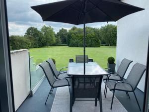 a table and chairs with an umbrella on a balcony at The Mews - Family space, garden, parking, balcony, view in Adlington