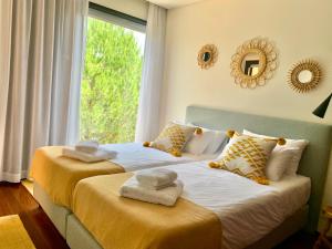 two beds in a room with a window at Vill'Amar Tróia in Troia