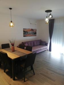 uma sala de estar com uma mesa e um sofá roxo em Apartments Vini em Donji Seget