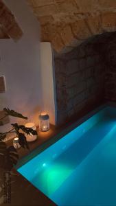 a blue swimming pool in a room with a brick wall at Luna Federiciana Luxury Room & Spa in Altamura