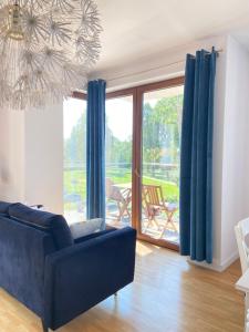 a living room with a blue couch and a large window at Ełk Blue Apartment przy promenadzie in Ełk