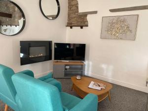 a living room with blue chairs and a tv at South Cottage - Garden, Views, Parking, Dogs, Cheshire, Walks, Family in Adlington