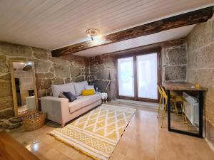 ein Wohnzimmer mit einem Sofa und einer Steinmauer in der Unterkunft A aira da xoaniña in Allariz