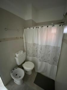 a bathroom with a toilet and a shower curtain at La Escala in Corrientes +2 photos