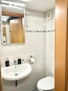 een badkamer met een wastafel, een toilet en een spiegel bij Mini Smart Studio - Self Check-in in Graz