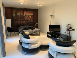 een woonkamer met banken en stoelen en een televisie bij Prachtige gastsuite in Ranst "Studio 34" in Ranst