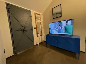uma sala de estar com televisão e uma cómoda azul com porta em Fra Storia e Modernità em Milão