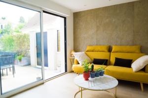 een woonkamer met een gele bank en een tafel bij EXIGEHOME - Chambre d'hôte avec jacuzzi et jardin paysagé, partagé in Orgeval