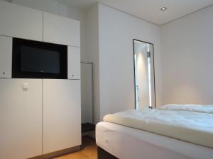 a white bedroom with a bed and a flat screen tv at Hotel Kloster-Gasthof Speinshart in Eschenbach in der Oberpfalz