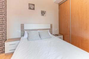 a bedroom with a white bed and a brick wall at Vivienda Teruel Mudejar in Teruel