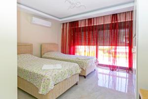 Zimmer mit 2 Betten und einem Fenster mit roten Vorhängen in der Unterkunft Paradise Town Villa Estella in Belek + 44 Fotos