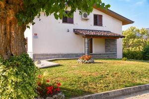 a white house with a tree in the yard at Pri Stari murvi in Vogrsko