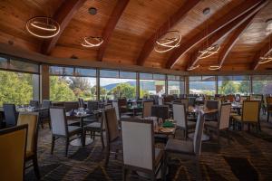 a dining room with tables and chairs and windows at Distinction Luxmore Hotel in Te Anau