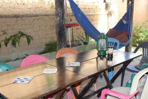 a wooden table with chairs and a bottle on it at Arte Vida Hostel Feminino in Itaúnas