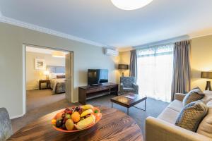 a living room with a bowl of fruit on a table at Distinction Hotel Rotorua in Rotorua