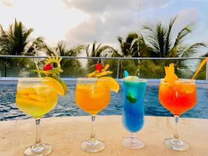 a group of four cocktails sitting on a table near the water at Hotel Boutique El Mirador in Arboletes