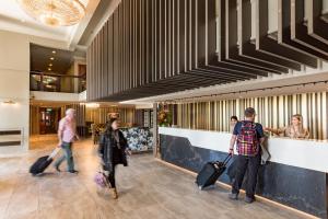 un groupe de personnes se promenant dans un hall avec bagages dans l'établissement Distinction Hotel Rotorua, à Rotorua