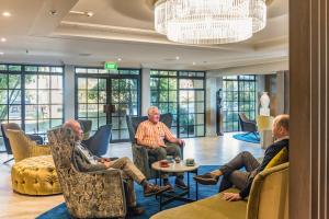 een groep mannen die in stoelen in een lobby zitten bij Distinction Hotel Rotorua in Rotorua