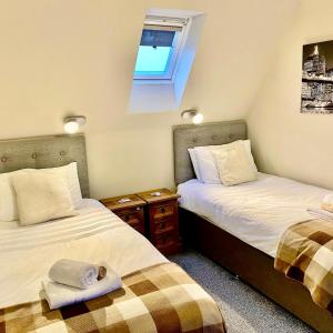 two twin beds in a room with a window at Skye View Cottage in Portree