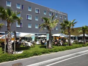 un hôtel avec des tables et des palmiers devant lui dans l'établissement Cosmopolitan Hotel, à Civitanova Marche