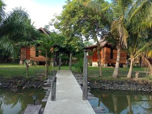 a walkway next to a house and a pond at Home Style Resort in Buriram
