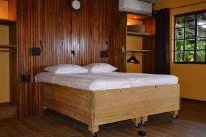 a bedroom with a wooden bed with white sheets at Jan Kok Lodges in Willibrordus