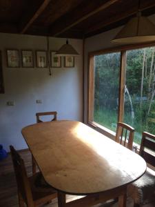 einen Holztisch und Stühle in einem Zimmer mit Fenster in der Unterkunft Cabaña en Río Puelo in Puelo