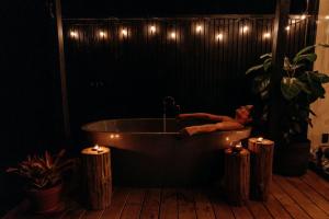 a man laying in a bath tub in a room with lights at Blackwood Cabin in Raglan