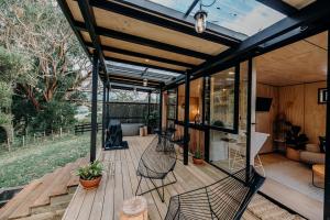 a screened in deck with chairs and a couch at Blackwood Cabin in Raglan