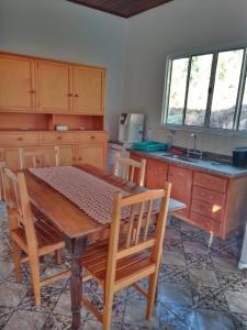 uma cozinha com uma mesa de madeira com cadeiras e um lavatório em Canto dos Pássaros- Casa de campo em Gonçalves em Gonçalves