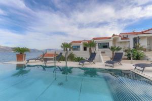 a swimming pool with chairs and a house at Villa Sun and Sea in Trogir